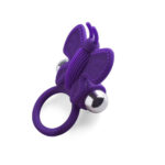 anello fallico vibrante in silicone viola elastico con appendice a farfalla per stimolazione clitoridea di coppia Butterfly Kinetic Shape vista prospettica ambientata sul letto